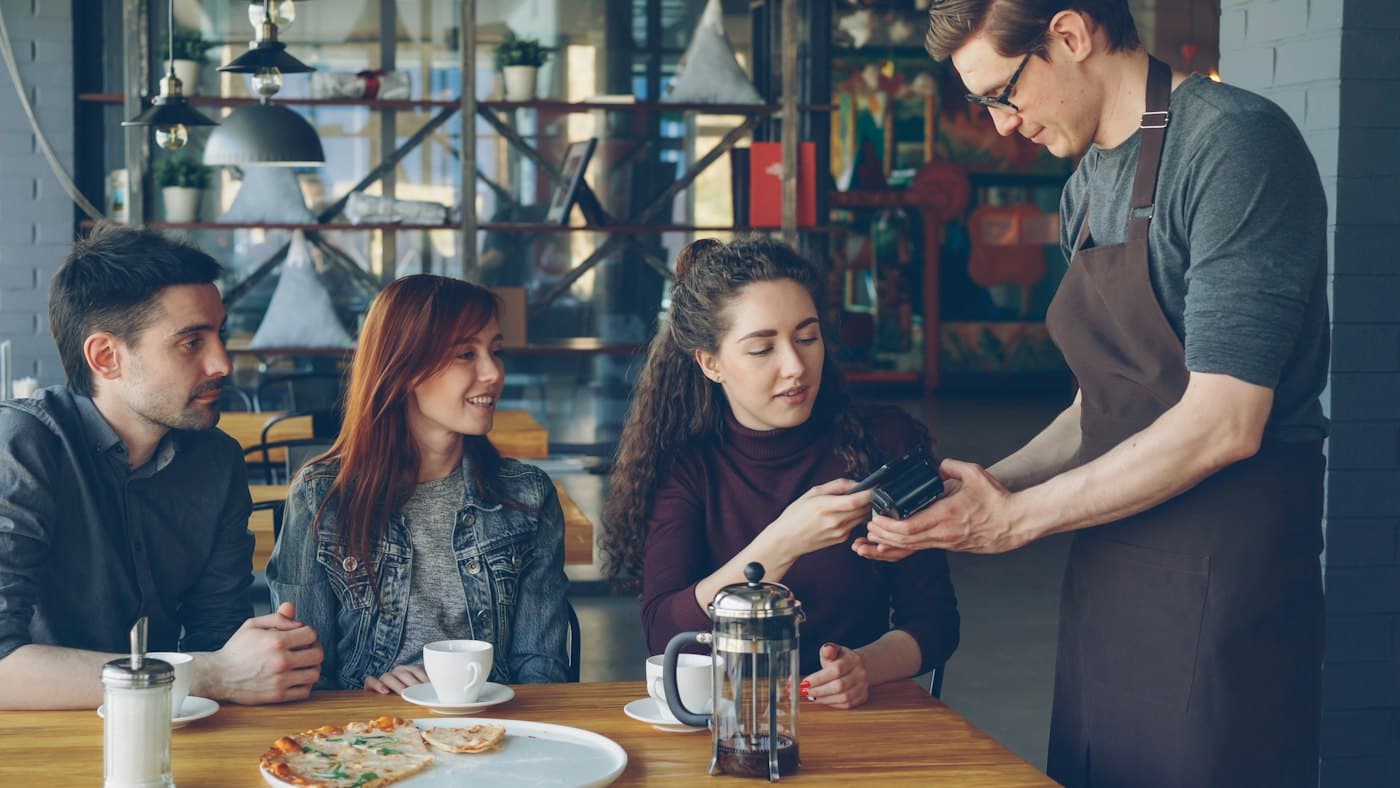 Mesero atendiendo a una clienta en un café
